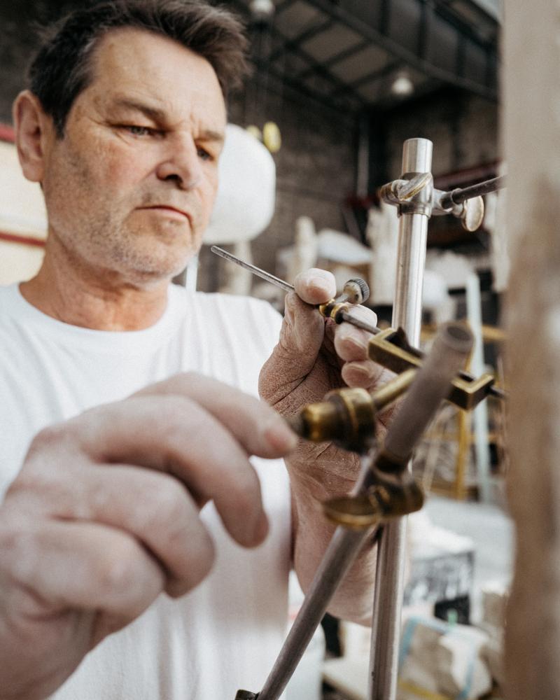 Stone mason's hands placing jig onto stone sculpture