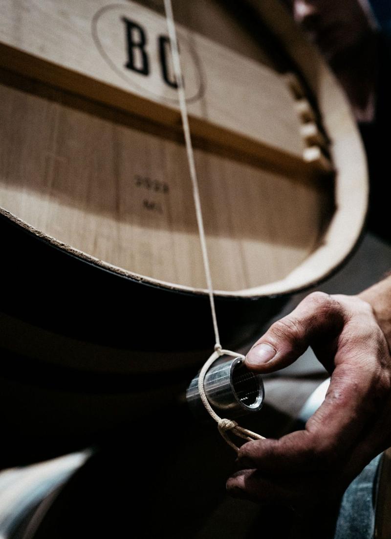 Close up of hand positioning lead weight for aligning wine barrels