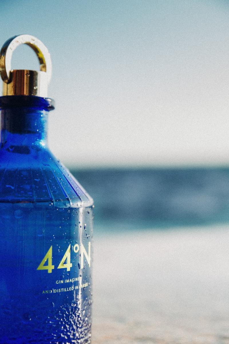 Bottle of Gin 44 seen from the side covered in splashes of water
