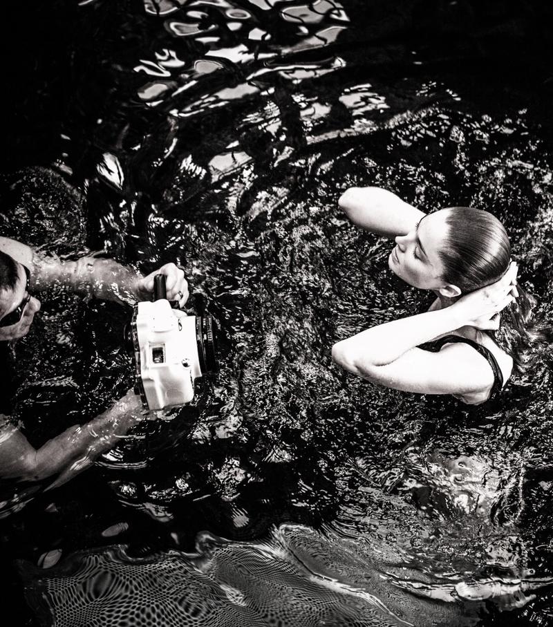 View from above of man filming girl surfacing in swimming pool