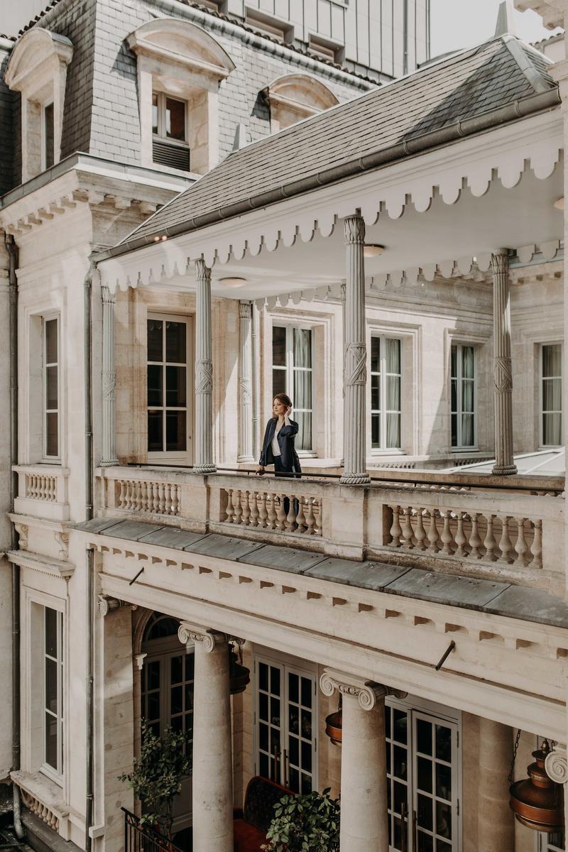 Girl standing on walkway across interior courtyard from afar