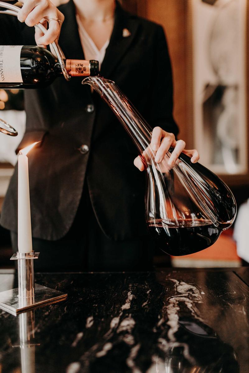 Portrait of sommelier decanting bottle of wine by candlelight