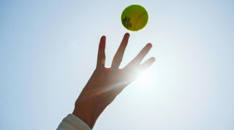 Still from Lanson x Wimbledon campaign, hand throwing tennis ball up into the air