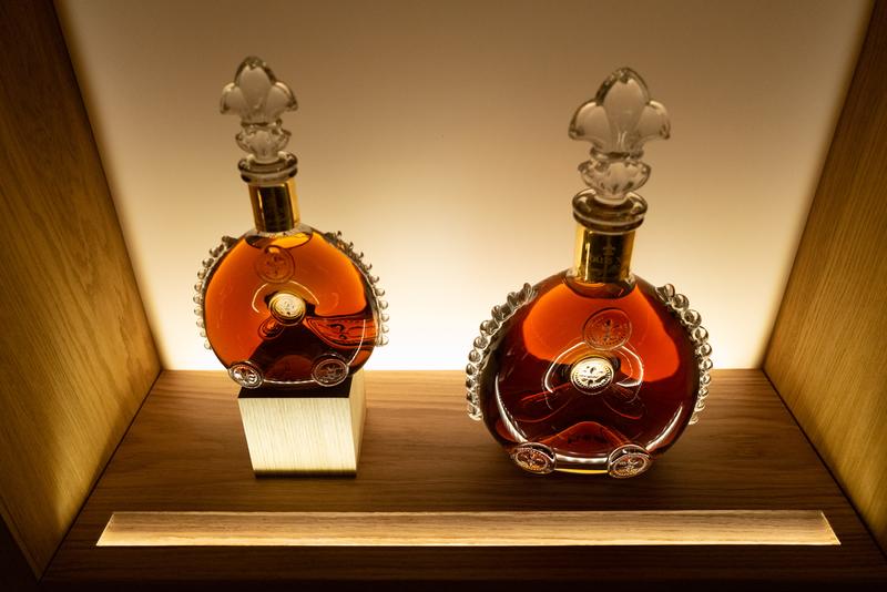 Two different sized LOUIS XIII cognac decanters sitting in a display cabinet