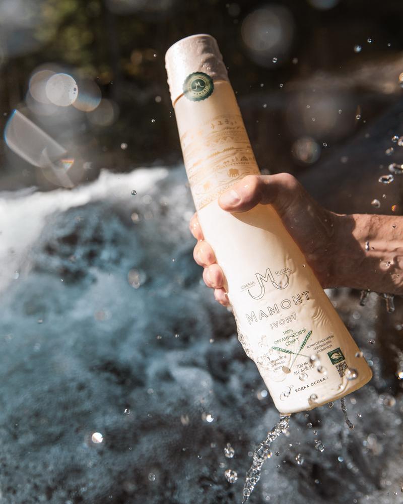Hand pulling bottle of Mamont Ivory vodka out of river with a splash