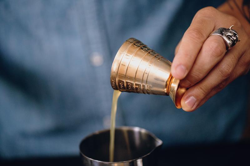 Macro of hand pouring a cocktail measure