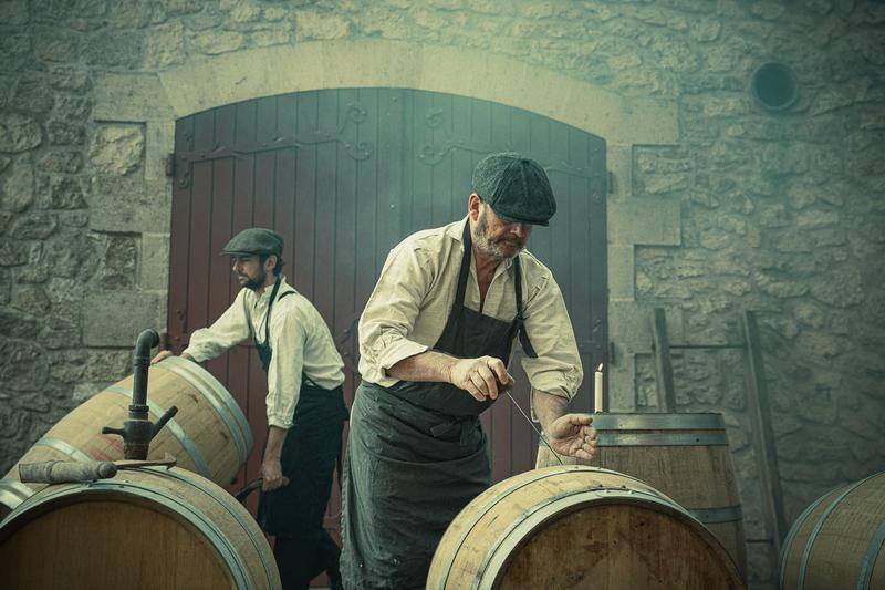 Two 1920s winemakers preparing and cleaning wine barrels