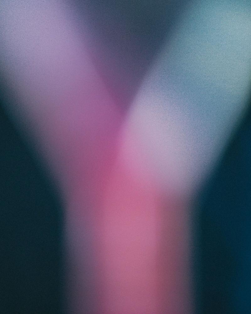 Out of focus wine glass showing pink blur against blue background