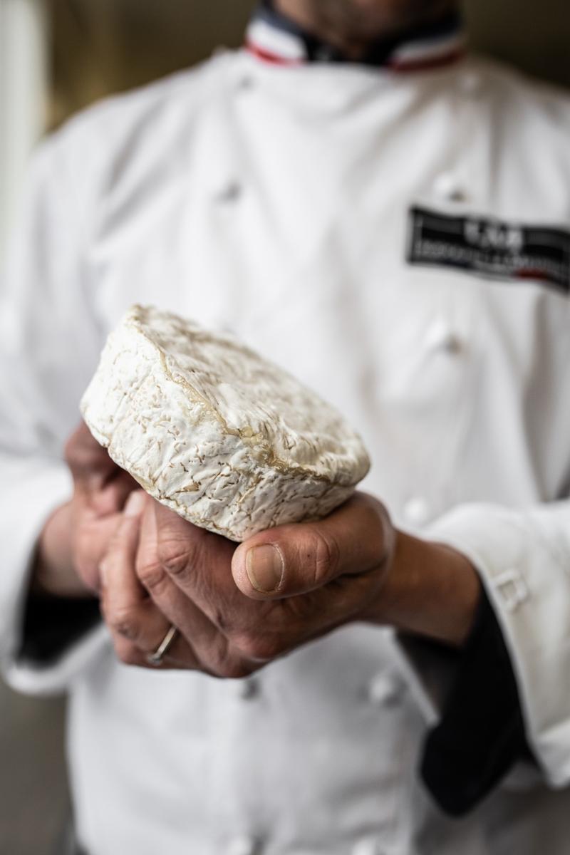 Close up of hands of Rodolphe Le Meunier holding camembert