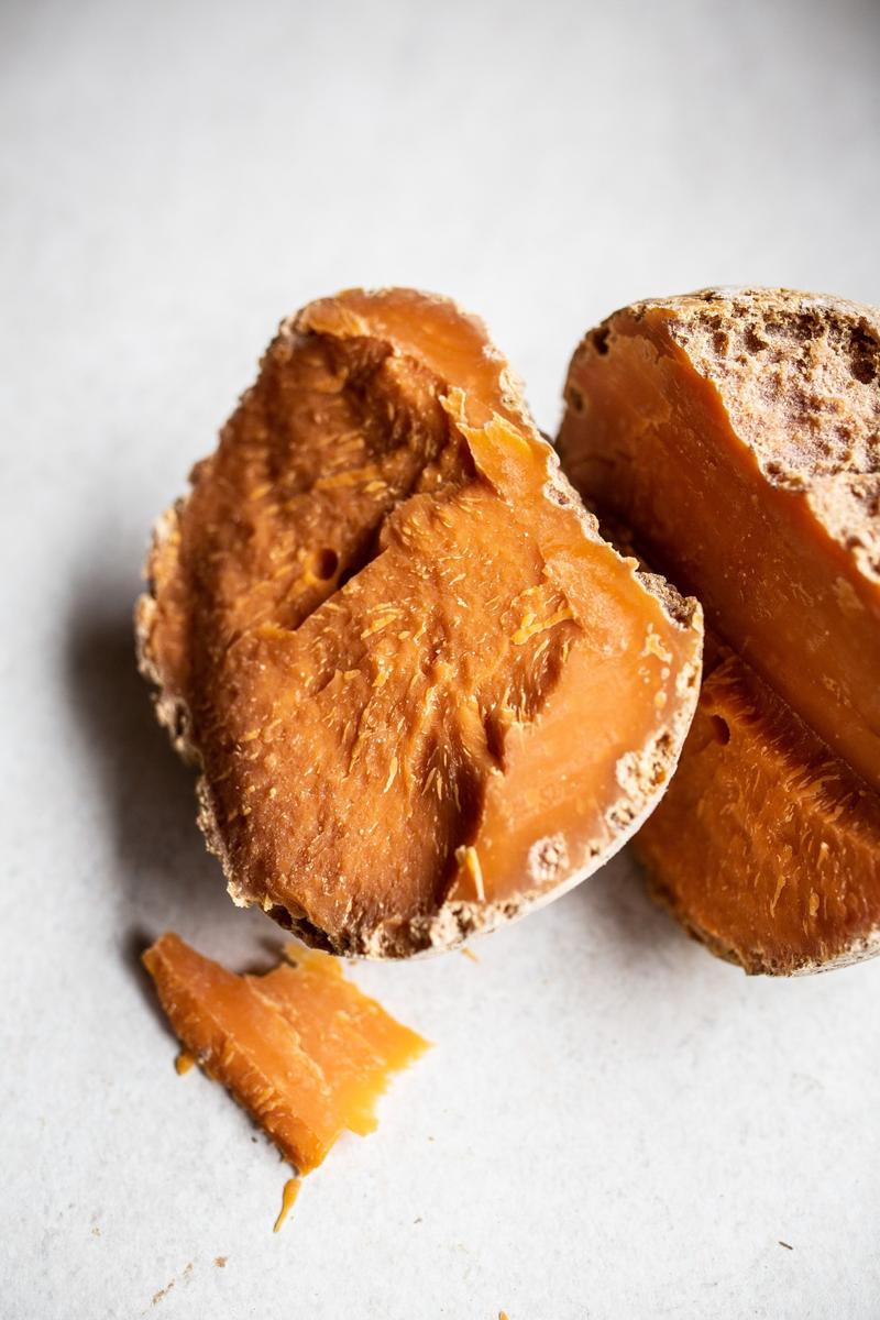 Close up of two pieces of Vieille Mimolette cracked open on white counter