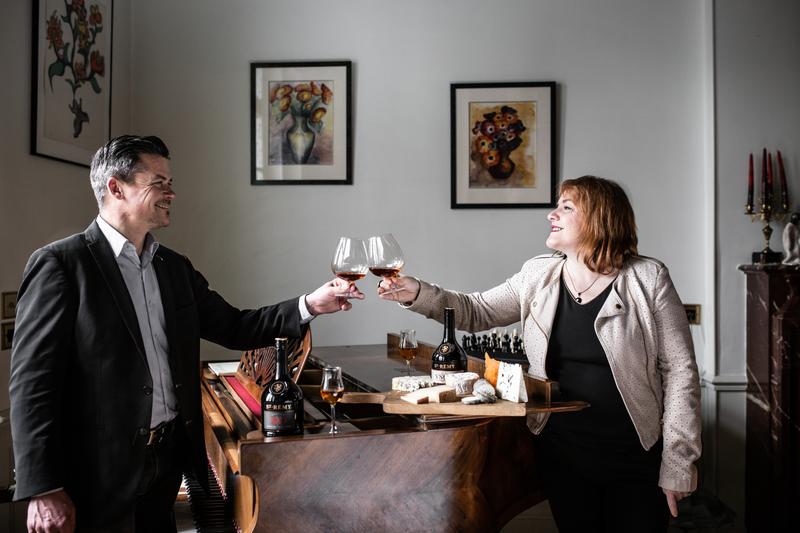 Cécile Roudaut and Rodolphe Le Meunier raising a glass of St-Rémy XO over a piano with cheese boards on top