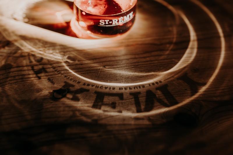 Close up of circular light projections on wooden table as sun shines through a glass of St-Rémy brandy