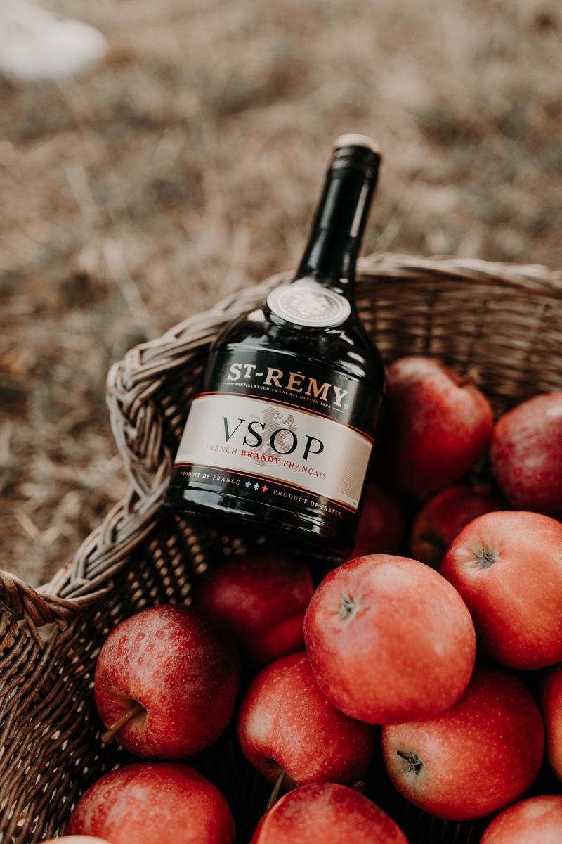 Close up of bottle of St-Rémy VSOP lying in basked of apples