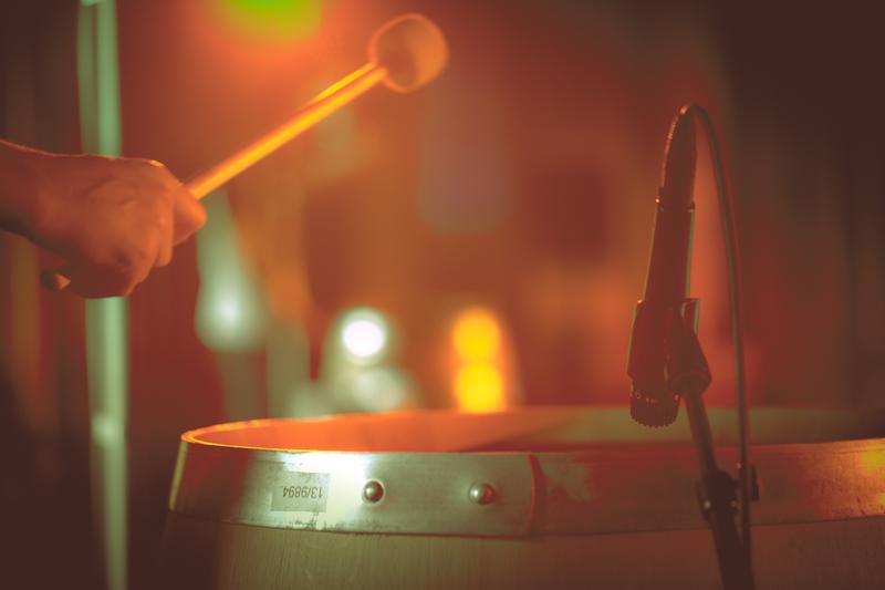 Hand hitting top of wooden barrel with drumstick