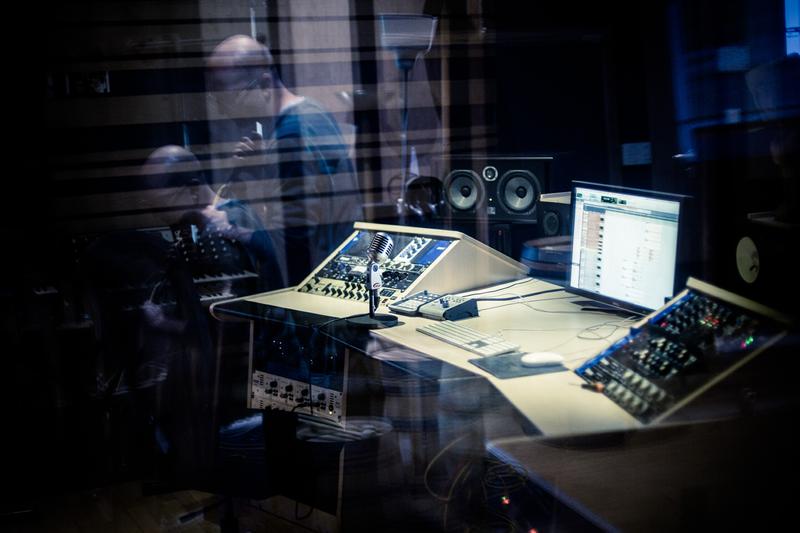 Reflection of sound engineer in window of mixing studio